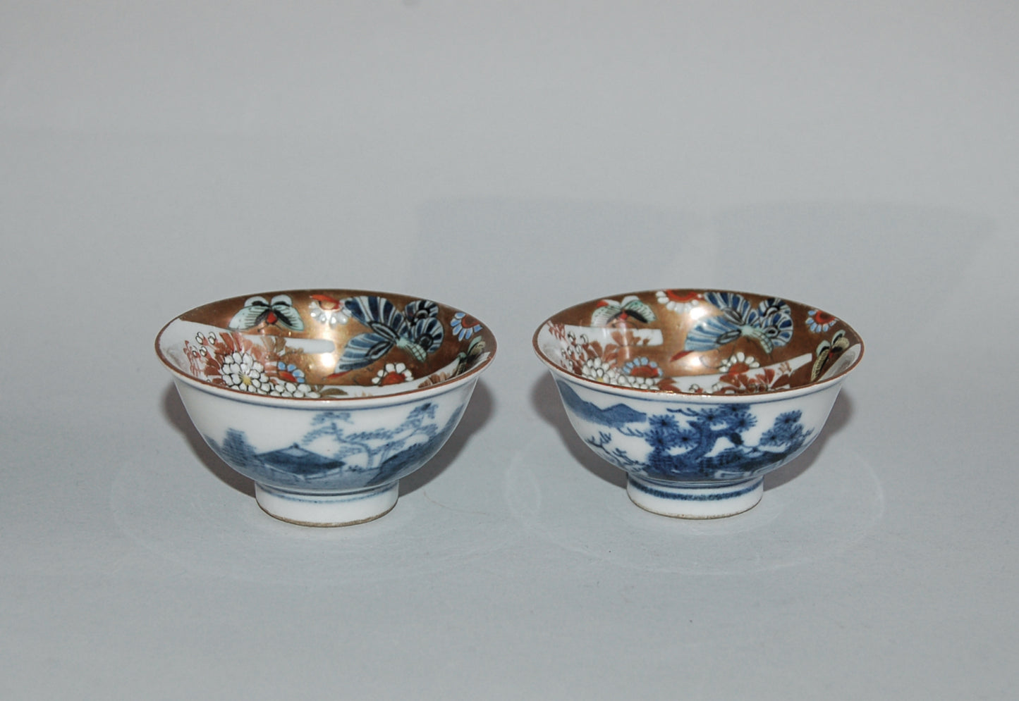 Pair of porcelain sake cups, birds, flowers, butterflies, riverscape, Kutani, Japan