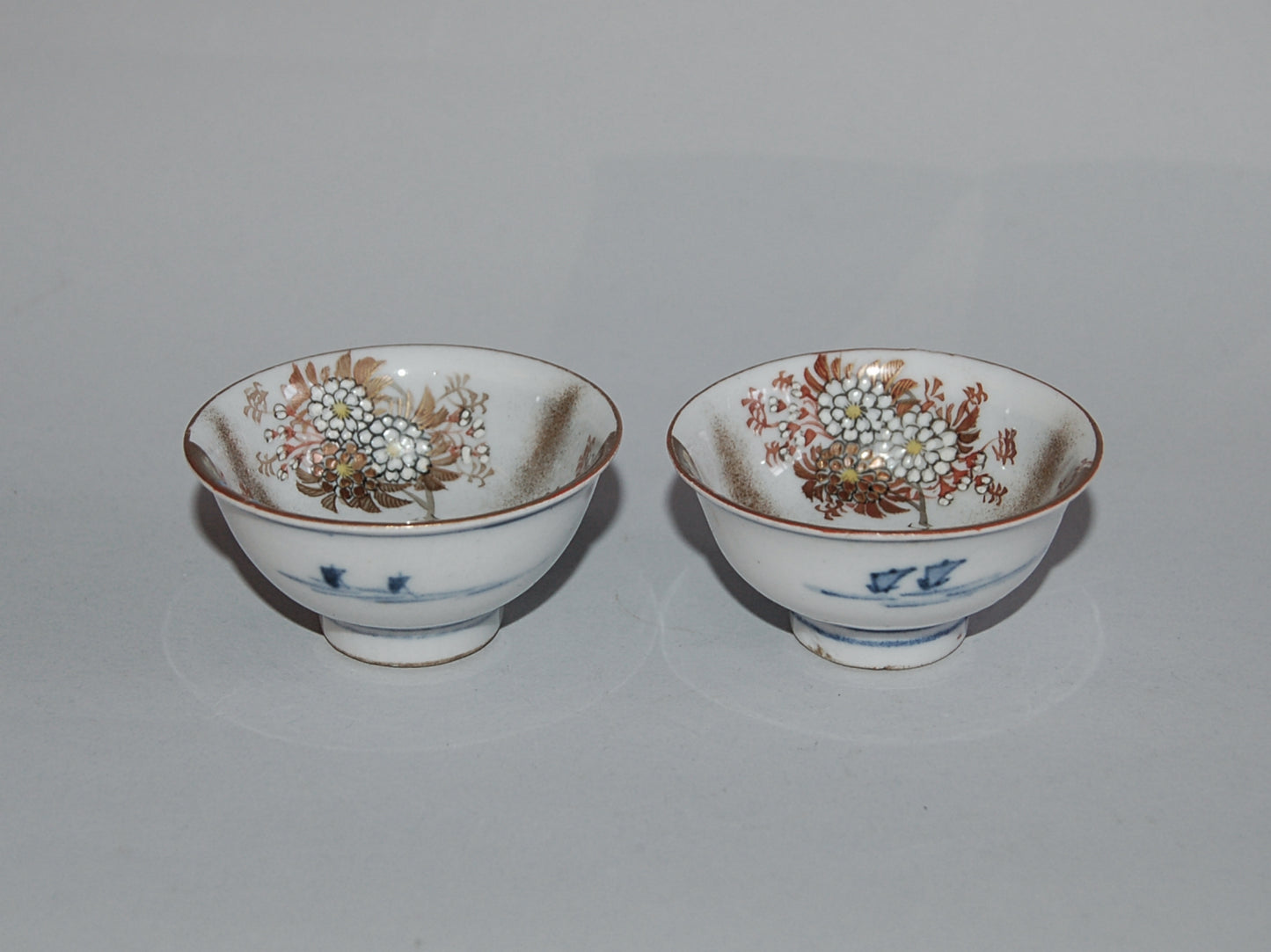 Pair of porcelain sake cups, birds, flowers, butterflies, riverscape, Kutani, Japan