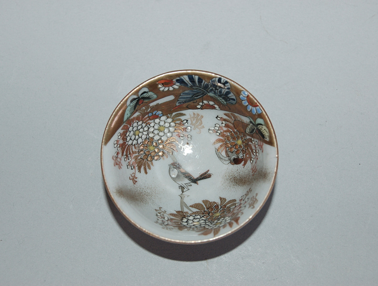 Pair of porcelain sake cups, birds, flowers, butterflies, riverscape, Kutani, Japan